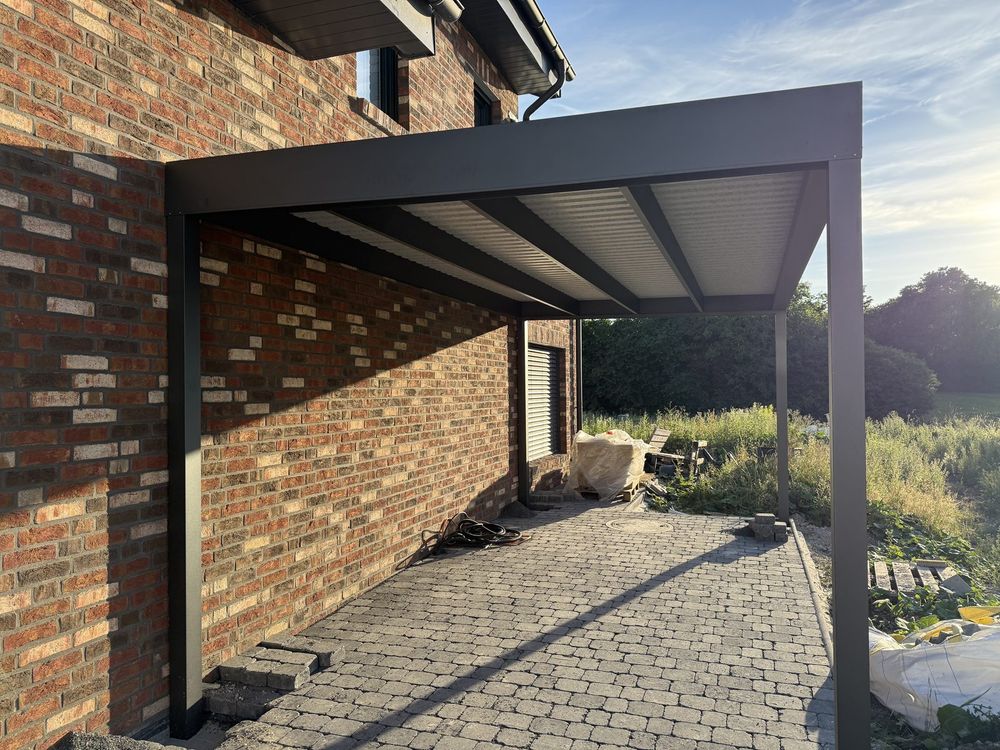 Carport aus Aluminium in Anthrazit an der Klinkerfassade über der gepflasterten Einfahrt
