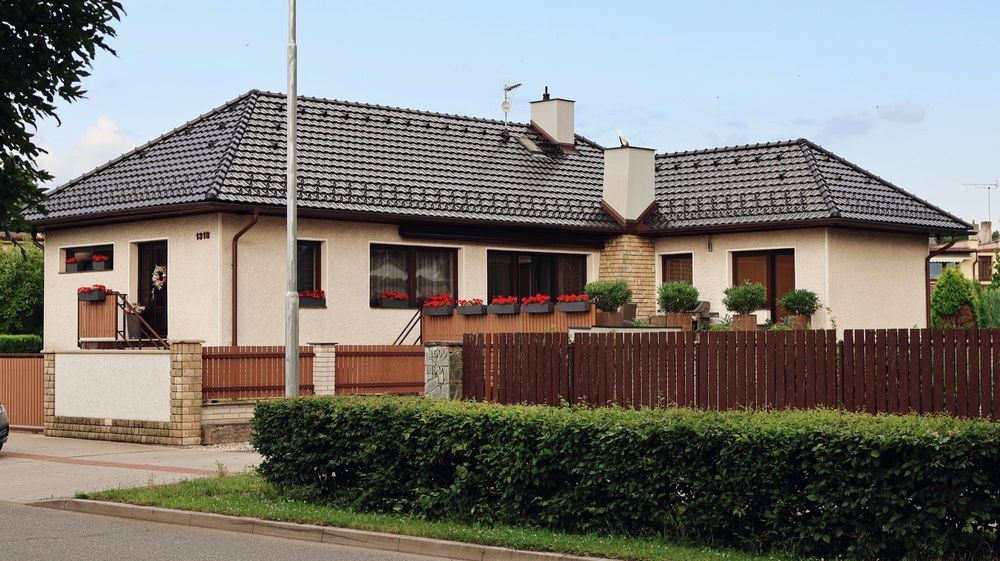Einfamilienhaus mit Walmdach, Zaun und Hecke am Grundstück