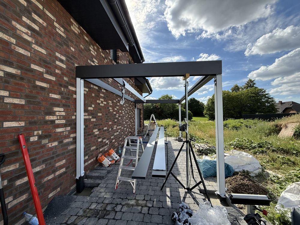 Montage eines Carports: Pfosten und Träger an der Klinkerwand